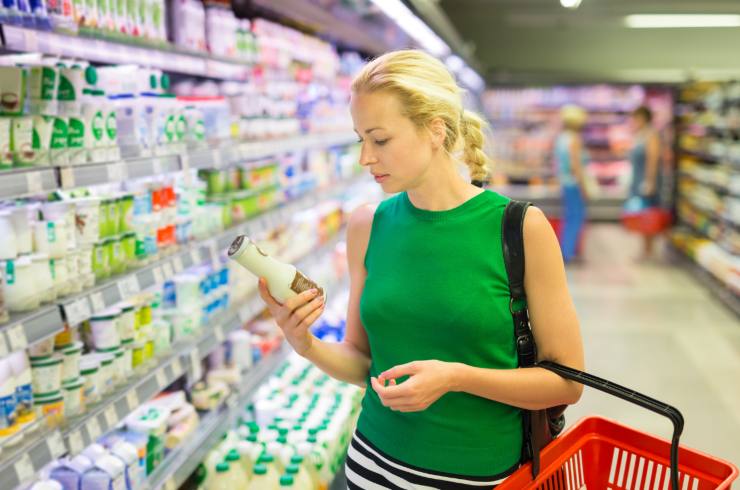 Donna bionda che guarda uno yogurt da bere nel reparto latticini