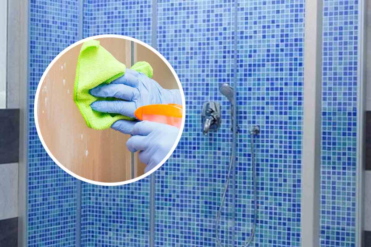 Un box doccia con piastrelle a mosaico azzurre e blu e, in evidenza, una mano che pulisce una doccia