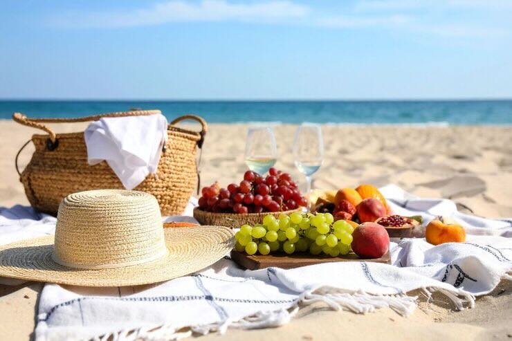 In spiaggia telo sulla sabbia con frutta, borsa, capello