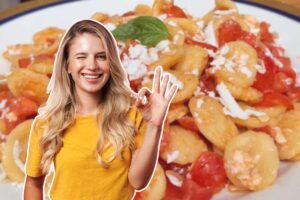 ragazza in primo piano e piatto di orecchiette con pomodorini