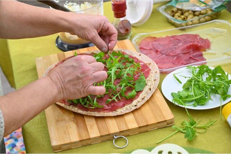 Farcire piadina con prosciutto crudo e rucola sul tagliere 